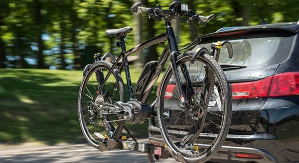 A eBike on a bike rack attached to the towbar and back of a big 4x4 car